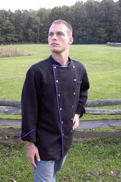 Chef Coat Style BSM100: Shown in Black 100% cotton petti point pique, left chest tailored welt pocket, blue suede piping (collar, front, cuffs, & pocket) & blue mussel buttons.