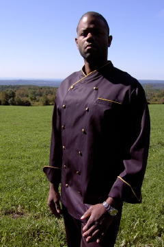Chef Coat Style CBM101: Shown in Black, 100% cotton Supima gabardine, left chest tailored welt pocket, cheviot gold piping (collar, cuffs & pocket) & brass buttons.