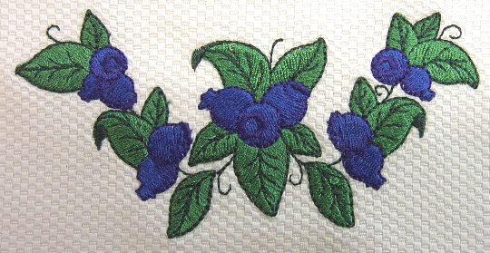 Close up image of embroidered blueberry wreath. Shown on 100% cotton petti point pique.